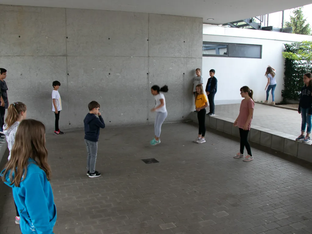 Jugendliche verteilen sich für eine Übung im Innenhof.